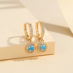 Détail des boucles d'oreilles créoles dorées avec pendentif turquoise et cristaux