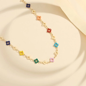 Gold clover necklace with colorful enamel pendants on a minimalist display stand