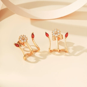 Detail van gouden bloemenoorbellen met rode marquise-stenen en micro-zirkonia's