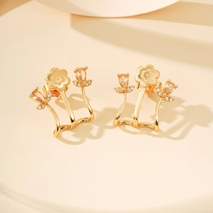 Macro-opname van de vergulde bloemoorbellen met champagne zirkoonstenen en bladdetails