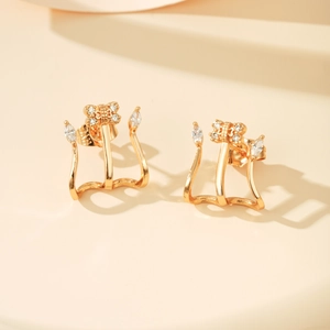 Detail van vergulde strik-ear cuffs met ronde en marquise geslepen zirkoon
