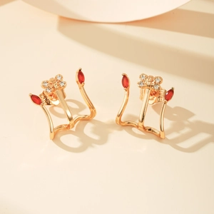 Detail van vergulde oorknopjes met rode marquise zirkoon en een vlinder in micro-pave