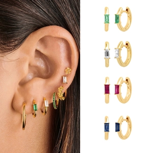 Details von goldenen Creolen mit bunten Zirkoniasteinen im modischen Stapel-Look