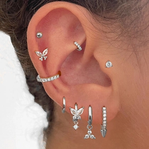 Close-up showing a variety of silver butterfly stud earrings and ear cuffs on the ear