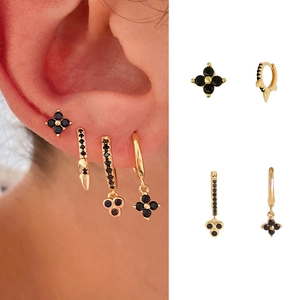 Macro detail of gold-plated silver earrings with black zircon four-leaf clover charms