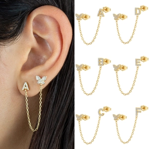 Detail of gold butterfly letter earrings with zircon stones and chain link connector