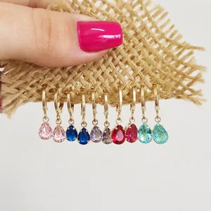 Detailed view of ten colorful teardrop gemstone earrings set in golden claw mounts
