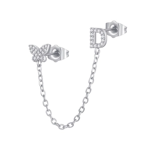 Macro detail of silver butterfly and letter D earring connected by a delicate chain