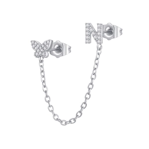 Macro detail of silver butterfly and letter N stud earrings with zircon linked by chain