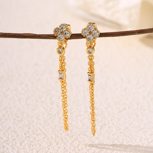Elegante gouden bloemknopjes met zirkonia pavé en hangende kwastjes aan een tak