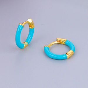 Detail van 24k vergulde huggie-oorbellen met levendig turquoise emaille afwerking