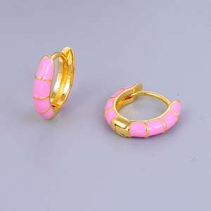 Dettaglio macro di orecchini a cerchio dorati con smalto rosa e trama stile bambù