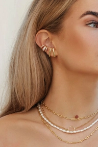 Dettaglio di collane d'oro a strati con perle e orecchini a clip su modella donna