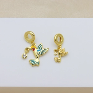Golden enamel hummingbird charms with blue wings and zircon accents on white podium