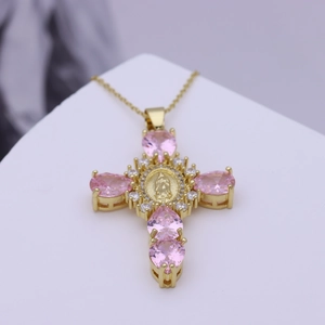 Makroaufnahme von Kreuzanhänger mit rosa Zirkonia und zentralem religiösem Ikonen-Detail