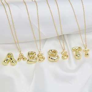 Macro shot of 18k gold plated bubble letter pendants on silky white satin fabric