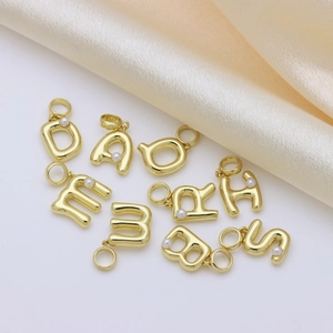 Pendentifs lettres initiales dorés avec perles sur fond élégant en satin couleur champagne