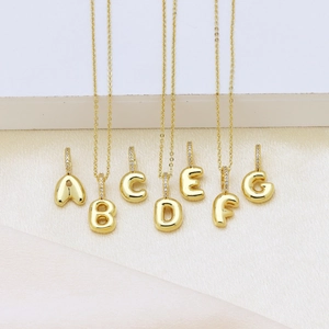 Detail of golden bubble letter pendants A-G with cubic zirconia on delicate chains