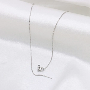 Collier chaîne à billes argentée avec pendentif cœur sur fond en soie blanche