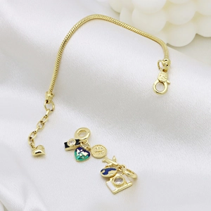 Bracelet chaîne serpent dorée avec breloques de voyage terre et appareil sur fond de soie