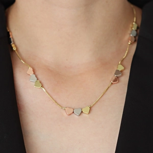 Collier à pendentifs cœurs tricolores avec chaîne dorée portée sur fond noir
