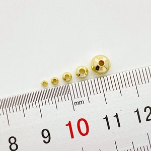 Close-up van 14K goudgevulde kralen in vijf maten met een liniaal voor DIY-sieraden