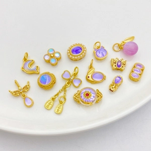 Detail of 18K gold butterfly and dolphin charms with purple moonstones on ceramic plate