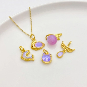 Detailed macro of 18K matte gold dolphin and butterfly pendants with moonstone inlay