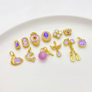 Macro shot of 18K gold butterfly and rabbit pendants with purple moonstones on white ceramic