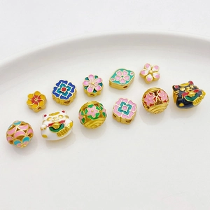 Detaillierte Makroansicht bunter Emaille-Blumen und Glückskatzen-Perlen für DIY-Schmuck
