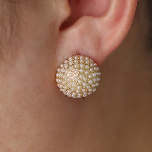 Dettaglio di modella con orecchini a semisfera dorati con perle finte incastonate a pavé
