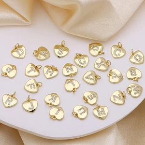 Goldenes Herzanhänger-Set mit A-Z Zirkon-Buchstaben auf elegantem champagnerfarbenem Seidenstoff
