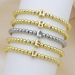 Braccialetti di perline con lettere a bolla in oro e argento su espositore bianco