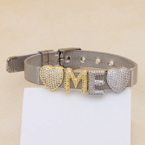 Silver mesh belt bracelet with crystal heart and sliding letters M and E on beige background