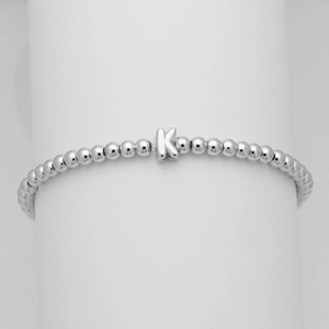 Dettaglio del bracciale con sfere d'argento e un ciondolo a lettera K stile palloncino