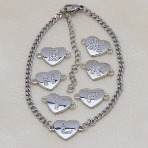 Close-up of silver Cuban link bracelet with heart-shaped pendants featuring zircon letters