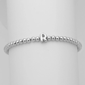 Dettaglio di un bracciale a sfere argentate con ciondolo a lettera R lucida su supporto bianco