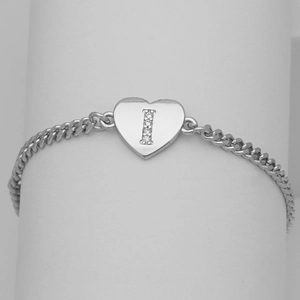 Close-up of heart charm with zircon-encrusted letter I on a silver Cuban link bracelet