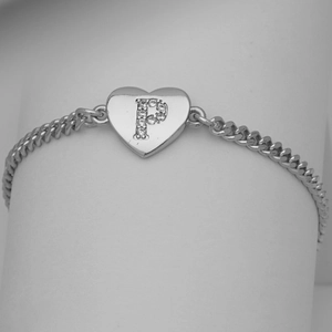 Macro detail of silver heart charm with cubic zirconia letter P on Cuban chain bracelet