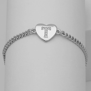 Detail of silver heart charm with cubic zirconia letter T on a sleek curb chain