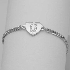 Macro view of silver Cuban chain bracelet with crystal-encrusted heart U-pendant