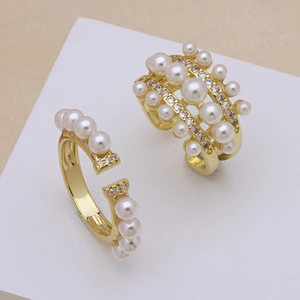 Elegant gold open ring featuring white pearls and zircon stones on a white stand