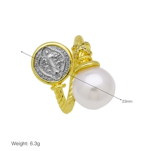 Detail of gold twisted ring featuring a white pearl, saint medal, and zircon accents