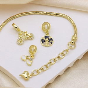 Gold snake chain bracelet with bicycle, starry sky, and rainbow cloud charms on marble
