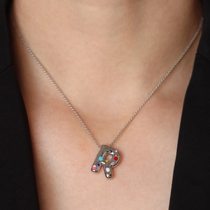 Zilveren ketting met letter R hanger en gekleurde emaille stippen gedragen door een model