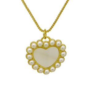Detalle de colgante de corazón dorado con nácar blanco y perlas en una cadena de caja