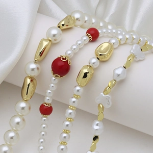 Elegant white pearl and red lantern bead necklaces with gold accents on silk display