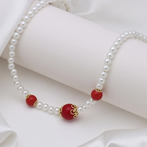 Detail of elegant pearl necklace with ornate red beads and golden floral spacers