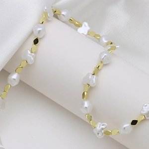 Elegant gold bead and pearl necklace wrapped on white silk display for luxury fashion