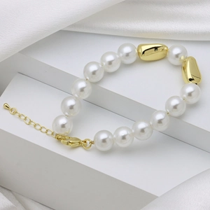 Detailed view of elegant white pearl bracelet with gold beads on white silk background